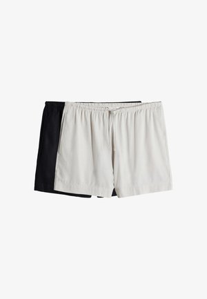 To par elastiske shorts med elastik i taljen, et lysegråt foran og et sort delvist synligt bagved på en hvid baggrund.