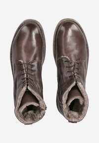 Bottes en cuir marron avec une finition lisse, un design à lacets et une doublure en fourrure douce visible à l'ouverture. Semelle robuste et bout rond.