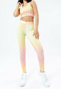 Pastel-gepatente sportoutfit bestaande uit een cropped tanktop en leggings, gemaakt van rekbare stof met een verloop van roze, geel en groen.