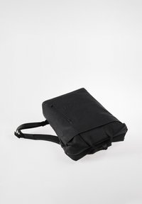 Black rectangular backpack with a front vertical zipper pocket, padded shoulder straps, and top carrying handles on a white background.