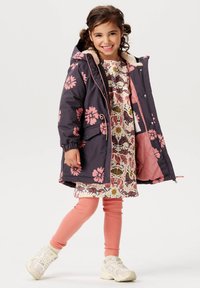 Flickors blommönstrade parka i mörk marinblå med rosa blommor, fodrad med mjuk rosa. Kombinerad med en dekorativ klänning och rosa ribbade leggings.