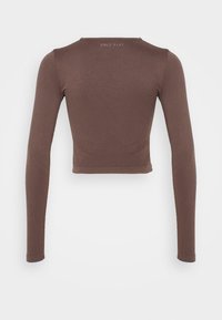 Ruskea pitkähihainen crop-top, jossa on sileä pinta, hienovarainen geometrinen kuvio hihoissa ja selässä sekä logo kaula-aukossa.