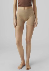 Pantaloni corti beige a vita alta realizzati in materiale elasticizzato, con una texture liscia e un design aderente. Dettaglio logo discreto vicino all'orlo.