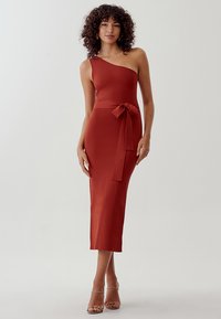Vestido rust de un solo hombro con una silueta ajustada, corte hasta la rodilla y un lazo decorativo en la cintura, confeccionado en una tela suave y elástica.