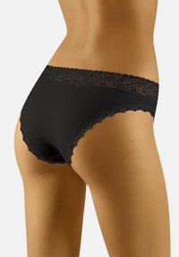 Mutande nere con bordo in pizzo, dalla vestibilità liscia, caratterizzate da un design ondulato lungo la vita e le gambe per un tocco di dettaglio.