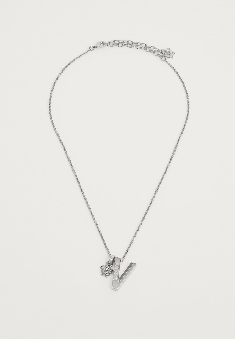 Sudraba kaklarota ar lielo "V" piekariņu, rotātu ar rhinestone akcentiem, piestiprināta pie smalkas ķēdes ar regulējamu aizdari.