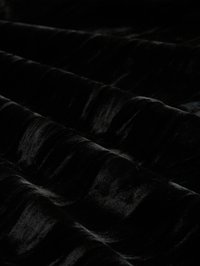 Zwarte fluweelstof met een zachte textuur, met subtiele glans en golfpatronen, gevouwen in plooien, die diepte en oppervlaktekwaliteit benadrukken.