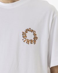 Weißes Baumwoll-T-Shirt mit kurzen Ärmeln, das auf der linken Brustseite ein kreisförmiges, orangefarbenes grafisches Textdesign zeigt. Glatte Textur.