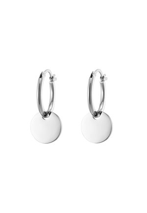 Paire de boucles d’oreilles créoles en argent, chacune avec un pendentif circulaire lisse et plat suspendu en bas de la créole.