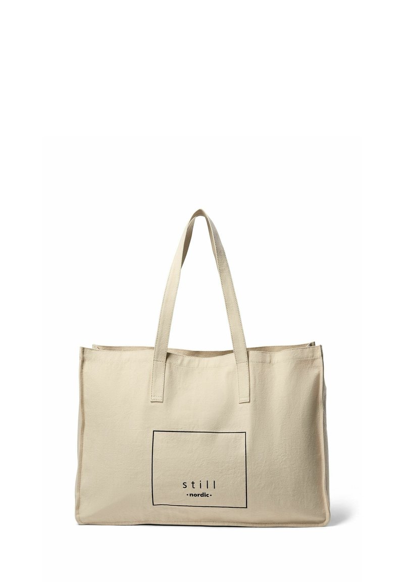 Beige Canvas-Tote mit zwei dünnen Griffen, die ein rechteckiges schwarzes Grafikdesign mit dem Text "still nordic" innerhalb des Rahmens zeigt.