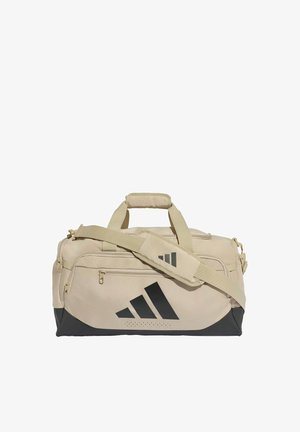 Beige ja musta värinen Adidas matkalaukku olkahihnalla ja etutaskulla, suunniteltu urheiluun tai matkustamiseen.