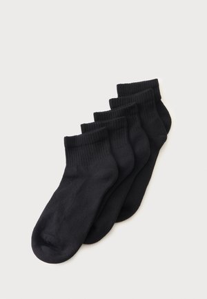 Cinq paires de chaussettes noires chevilles empilées avec des bords-côtes sur fond blanc.