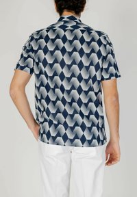 Camicetta a maniche corte con un motivo geometrico a zigzag blu e bianco, realizzata in tessuto morbido con una vestibilità comoda e colletto a punta.