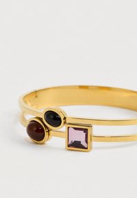 Χρυσό βραχιόλι με δύο λωρίδες, που διαθέτει τρεις λίθους σε στεφάνη: ένας ροζ τετράγωνος, ένας μαύρος οβάλ και ένας στρογγυλός σκούρος κόκκινος.