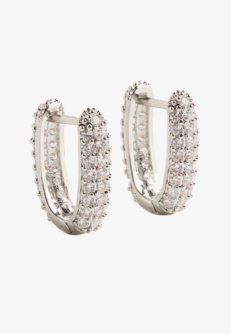 Srebrne kolczyki w kształcie kół z teksturowaną powierzchnią, ozdobione małymi, przezroczystymi kryształkami na zewnętrznych brzegach, tworzącymi lśniący efekt.