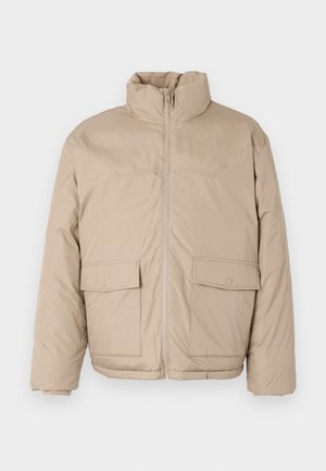 Beige padded jacket featuring a high collar, front zipper, and two large flap pockets. Smooth texture and slightly oversized design.