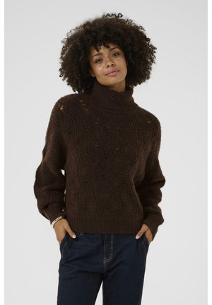 Brauner, gestrickter Rollkragenpullover mit einem strukturierten Muster und gerippten Bündchen, kombiniert mit dunkelblauen Jeans im lässigen Schnitt.