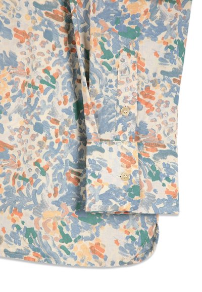 Poignet de chemise à manches longues avec boutons, présentant un motif abstrait multicolore en bleu, vert, orange et beige sur un tissu clair.
