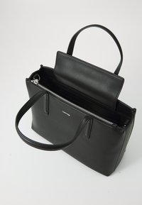 Borsa a mano in pelle nera con due manici, chiusura con zip e scomparto aperto. Presenta un design minimalista e una texture liscia e sobria.