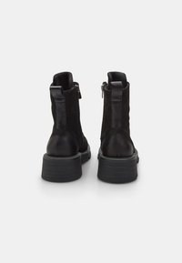 Stivali ankle neri in pelle con finitura texturizzata, tacco spesso e zip laterale. Design elegante con dettagli in pelle liscia a contrasto.