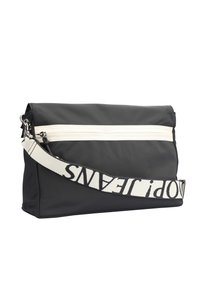 Borsa in nylon nera con una cerniera bianca frontale, dotata di una larga tracolla nera e bianca con lettere. Design semplice e rettangolare con texture liscia.