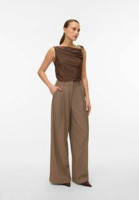 Bronzinės tekstūruotos viršutinės dalies audinys su drapiruotėmis ir peties raiščiu; bežinės aukštu liemeniu plačios kelnės su priekinėmis raukšlėmis ir šoninėmis kišenėmis.