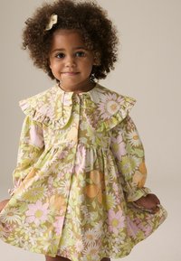 Blumenkleid mit grünem Grund, pinken und orangenen Blumen, Rüschensaum, langen Ärmeln und knopfverzierung.