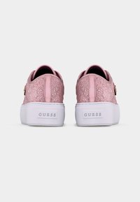 Paire de baskets compensées texturées roses avec semelles blanches et logo "GUESS" sur le talon, vues de derrière.