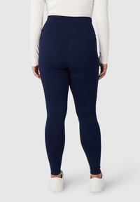 Leggings blu navy a vita alta realizzate in tessuto elasticizzato, design aderente, texture liscia, senza motivi o elementi visibili.