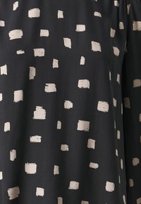 Črn material z razpršeno obliko nepravilnih bež črtastih kvadratov. Gladka tekstura z mehkobo in lahkotnim videzom.