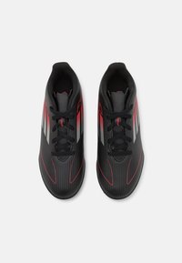 Schwarze Sportschuhe mit einem eleganten Design, ausgestattet mit roten und silbernen Akzenten, gerippter Textur und traditionellen Schnürsenkeln für einen sicheren Sitz.