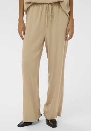 Beežid, lahtised püksid, mis on valmistatud kergest kangast, esindades nööriga vööd ja sirgeid, voolavaid säärtega. Mustad teravaotsalised kingad viimistlevad välimuse.