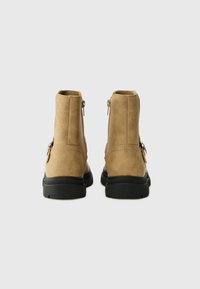 Botas de tobillo de imitación de cuero en tono marrón, con un acabado suave, cierre de cremallera y suelas de goma negra. Presentan un acento metálico en el lateral.