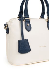 Borsa bianca strutturata con dettagli blu navy, dotata di due manici, hardware dorato e un'etichetta piccola. Nome del marchio "HEXAGONA" stampato in oro.