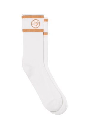 Paire de chaussettes blanches montantes avec deux bandes orange et un logo circulaire Roland Garros Paris près du bord supérieur.