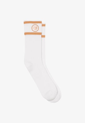 Paire de chaussettes blanches montantes avec deux bandes orange et un logo circulaire Roland Garros Paris près du bord supérieur.
