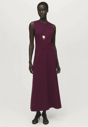 Burgundy sleeveless dress with a fitted bodice and flared skirt, made of smooth fabric. A gold pendant necklace adds a distinct accent.