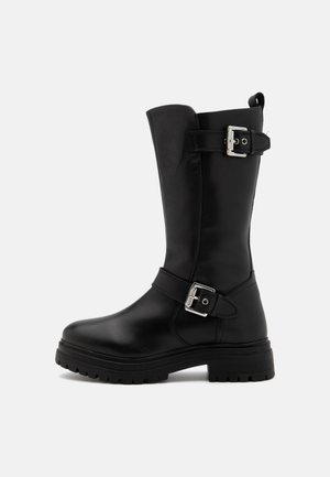 Črne usnjene škornje do kolen s zaobljenim prstom, stranskimi zaponkami in debelim gumijastim podplatom, ki ima teksturiran vzorec.