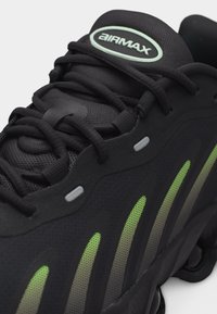 Μαύρο αθλητικό παπούτσι Air Max με μαύρα κορδόνια, γλώσσα από δίχτυ και ρίγες με διαβάθμιση από νέον πράσινο στο πλάι.