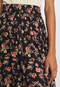 Jupe noire à motifs floraux avec une taille élastique froncée, ornée de fleurs multicolores et de motifs feuillus, fabriquée en tissu doux.