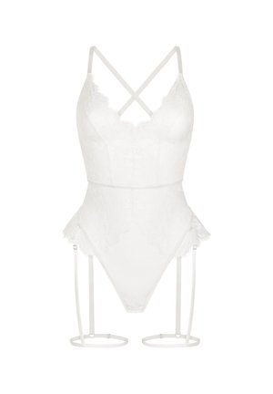 Body en lingerie blanche en dentelle avec bretelles croisées, bords festonnés, jambes échancrées et jarretelles attachées avec des anneaux circulaires autour des cuisses.