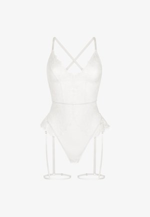 Body en lingerie blanche en dentelle avec bretelles croisées, bords festonnés, jambes échancrées et jarretelles attachées avec des anneaux circulaires autour des cuisses.