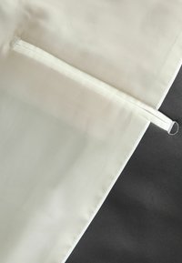 Light beige and dark gray fabric with a smooth texture, featuring a vertical seam and a narrow white accent strip.