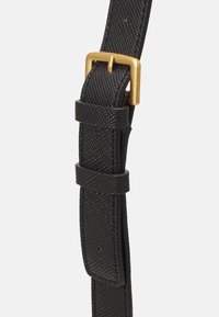 Ceinture en cuir noir texturé avec deux boucles et une boucle en métal rectangulaire dorée sur fond blanc.