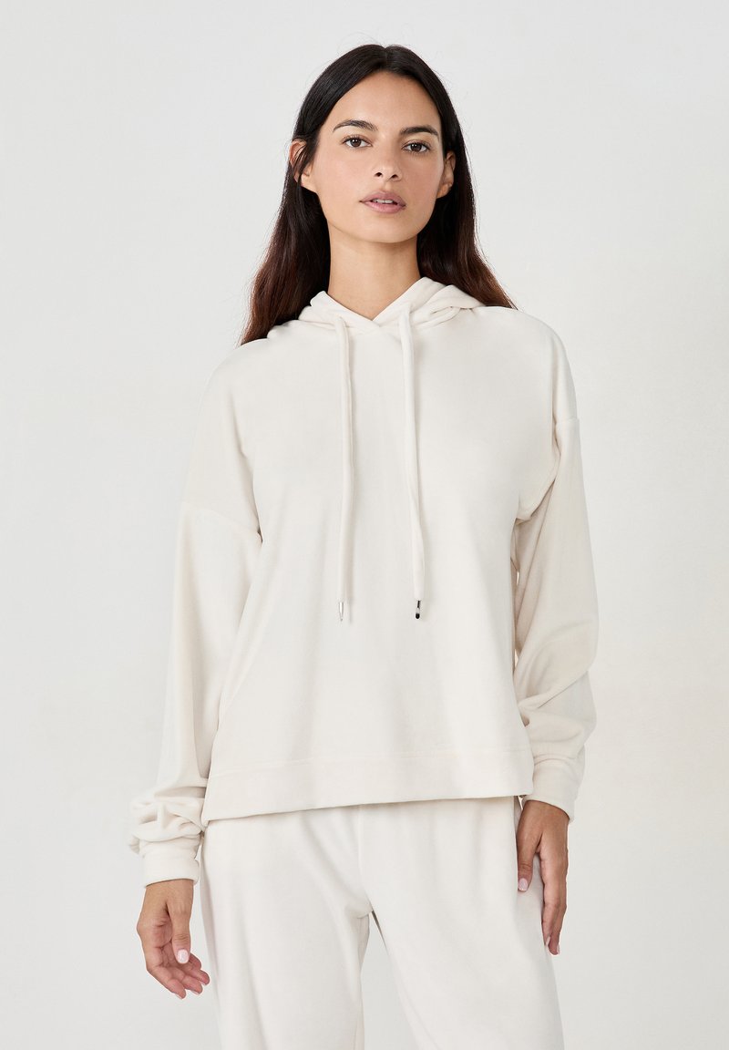 Cremfarbener Hoodie aus weichem Stoff, mit Kordelzugkapuze, lockerer Passform und gerippten Bündchen. Das Design ist minimalistisch und nahtlos.