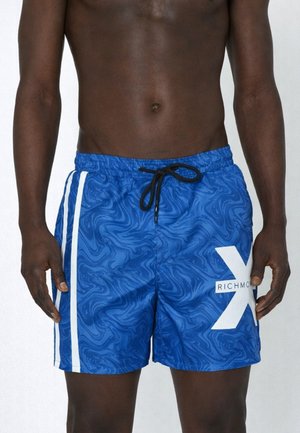 Torace maschile che indossa pantaloncini da bagno blu con motivo astratto a spirale, strisce laterali bianche, coulisse nera e logo bianco "Richmond" sulla gamba destra.