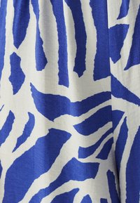 Sininen ja valkoinen kangas, jossa on rohkea, abstrakti seeprahakuvio. Pintakuvio on sileä ja siinä on hieman kiiltoa. Materiaali näyttää kevyeltä ja virtaavalta.