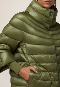 Olivgrüne gepolsterte Jacke mit hohem Kragen, horizontal gestepptem Design, glatter Textur und einer Seitentasche.