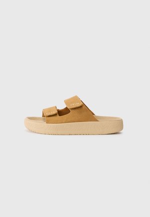 Tan suede sandals with two adjustable Velcro straps and textured beige rubber sole featuring a wave pattern.