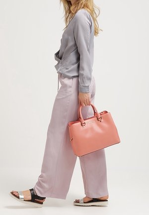 Rosa Lederhandtasche mit doppelten Obergriffen, rechteckiger Form und glatter Textur. Kombiniert mit helllila Schlaghosen und einer grauen Bluse.